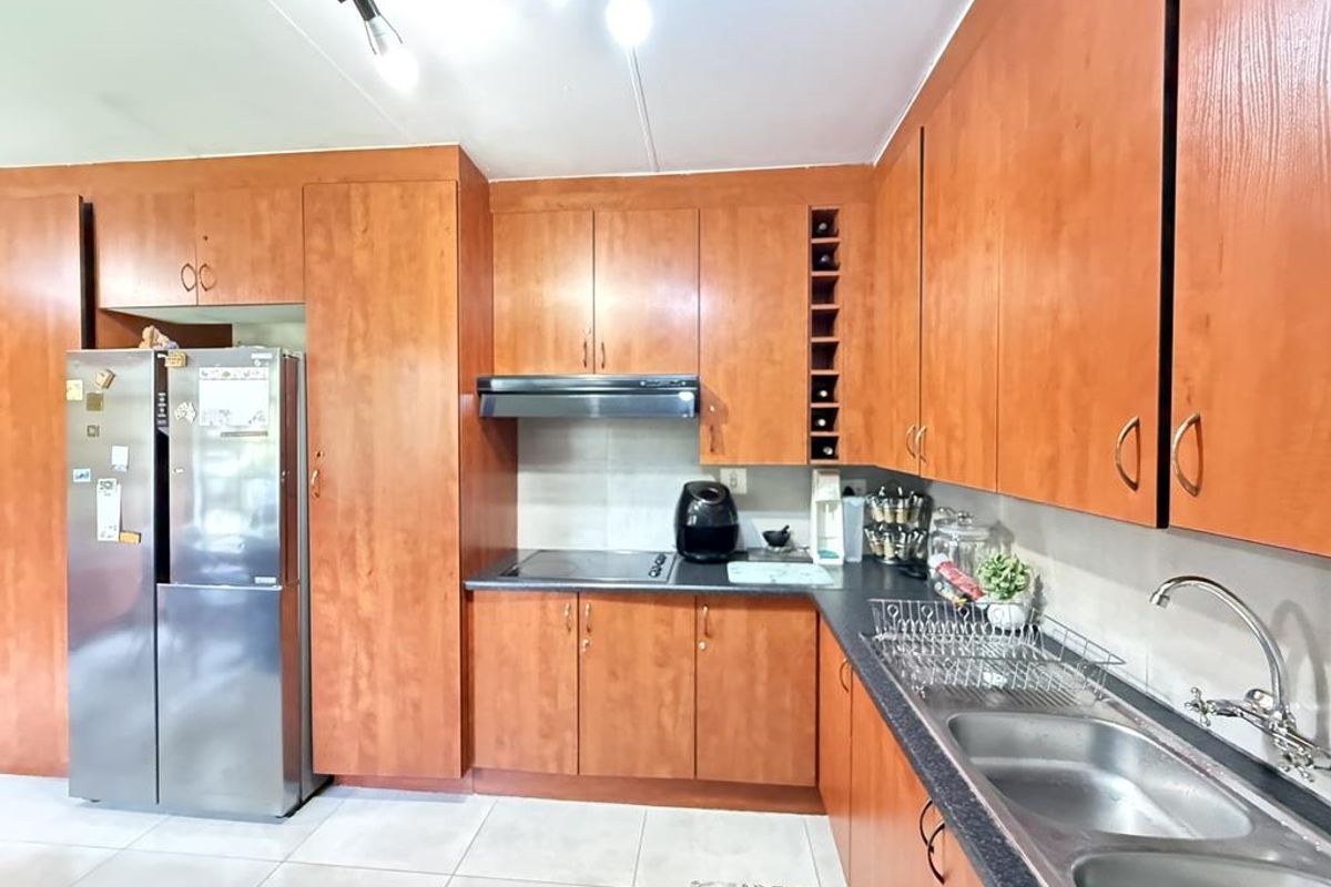 A functional kitchen featuring wood-look cabinetry, laminate countertops, a double stainless steel sink, and a built-in extractor fan.
