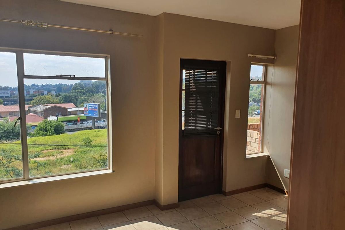 A bright, empty living area featuring tiled flooring, large windows with natural light, and direct access to an exterior space.