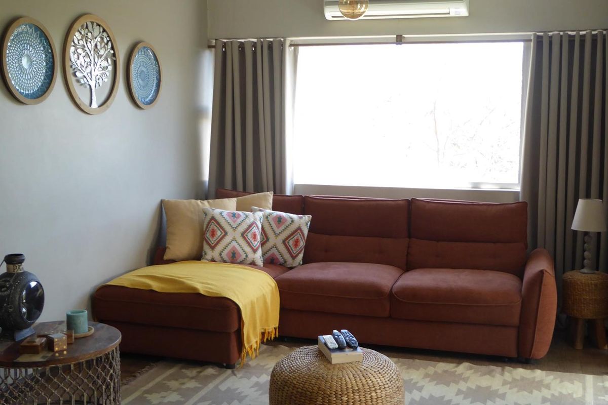 A comfortable living room featuring a large window with curtain tracks and a wall-mounted split-system air conditioning unit.