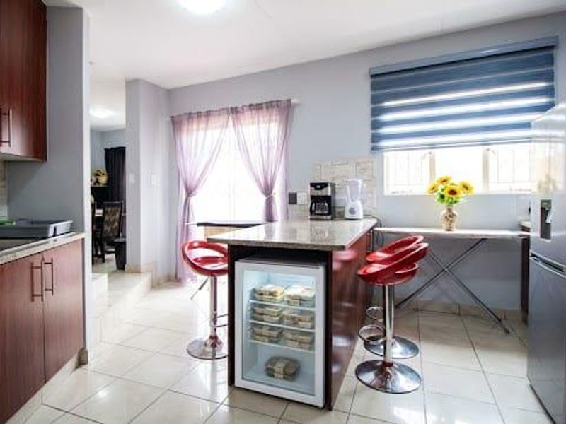 A functional kitchen featuring dark wood cabinetry, granite countertops, tiled flooring, and an integrated undercounter fridge, offering a practical layout for daily use.