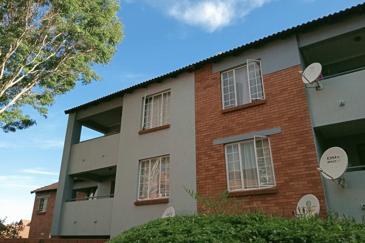 Exterior view of a multi-story apartment building featuring a combination of brick and painted plaster facade with balconies and satellite dish installations.