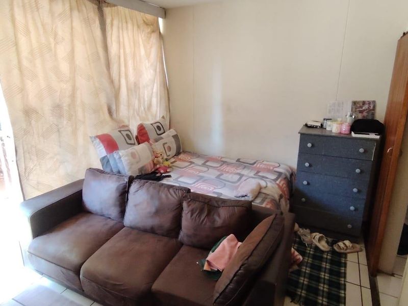 A bedroom featuring tiled flooring and a sliding door leading to an outdoor area, requiring cosmetic updates to improve its overall condition.