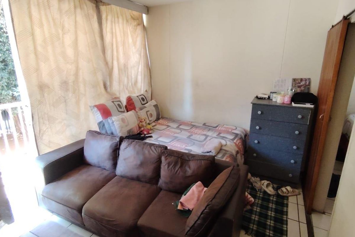 A bedroom featuring tiled flooring and a sliding door leading to an outdoor area, requiring cosmetic updates to improve its overall condition.