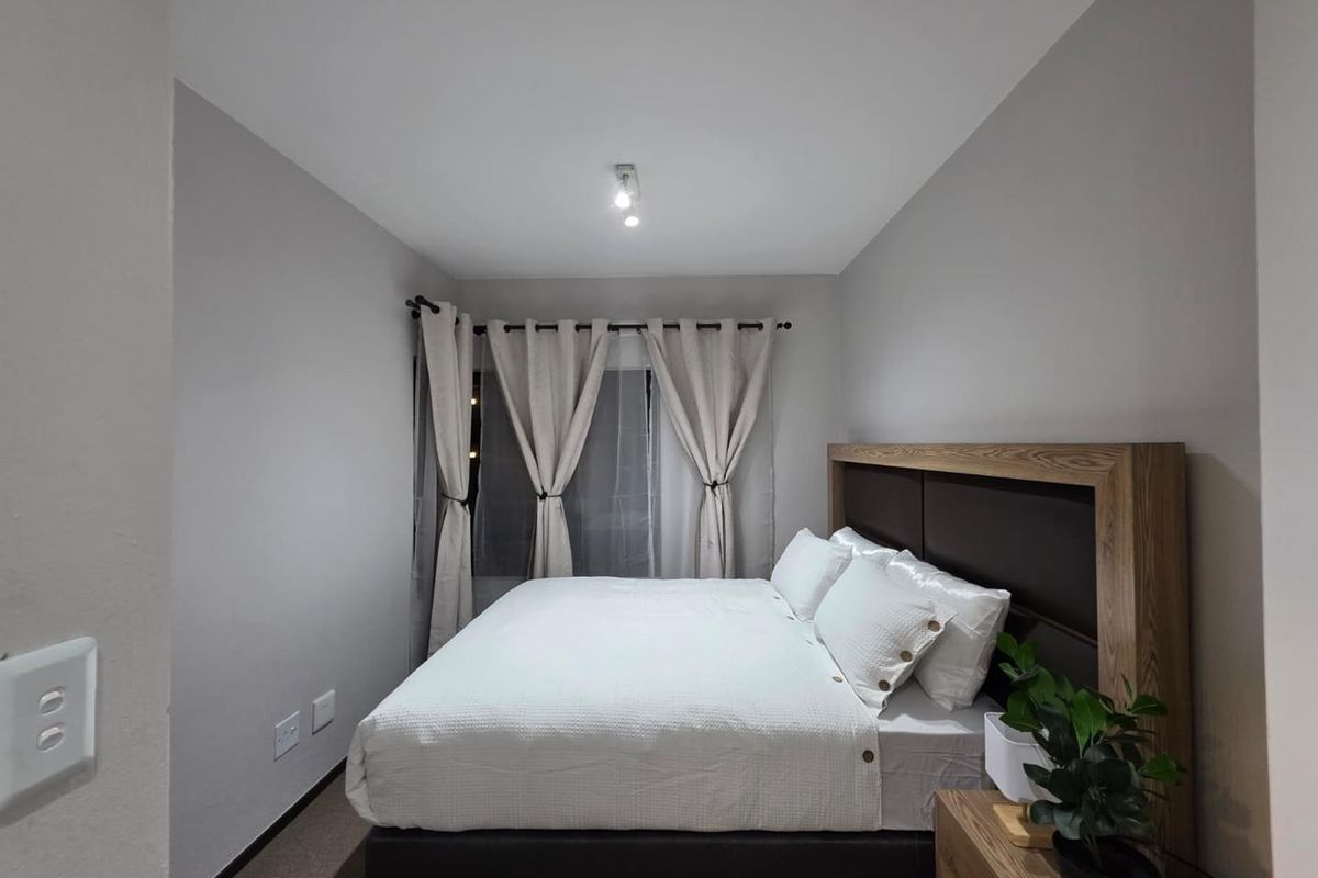 A well-maintained bedroom featuring neutral wall tones, a central ceiling light fixture, and standard electrical fittings.