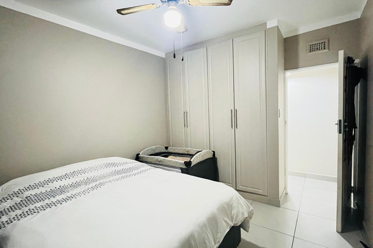 A well-maintained bedroom featuring built-in floor-to-ceiling cabinetry, tiled flooring, and a ceiling fan.