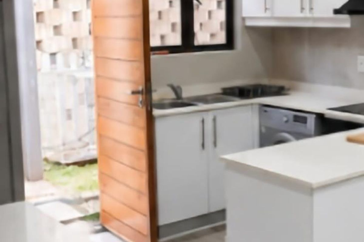 Modern kitchen featuring white cabinetry, stone countertops, integrated appliances, and direct access to an outdoor area through a timber door.