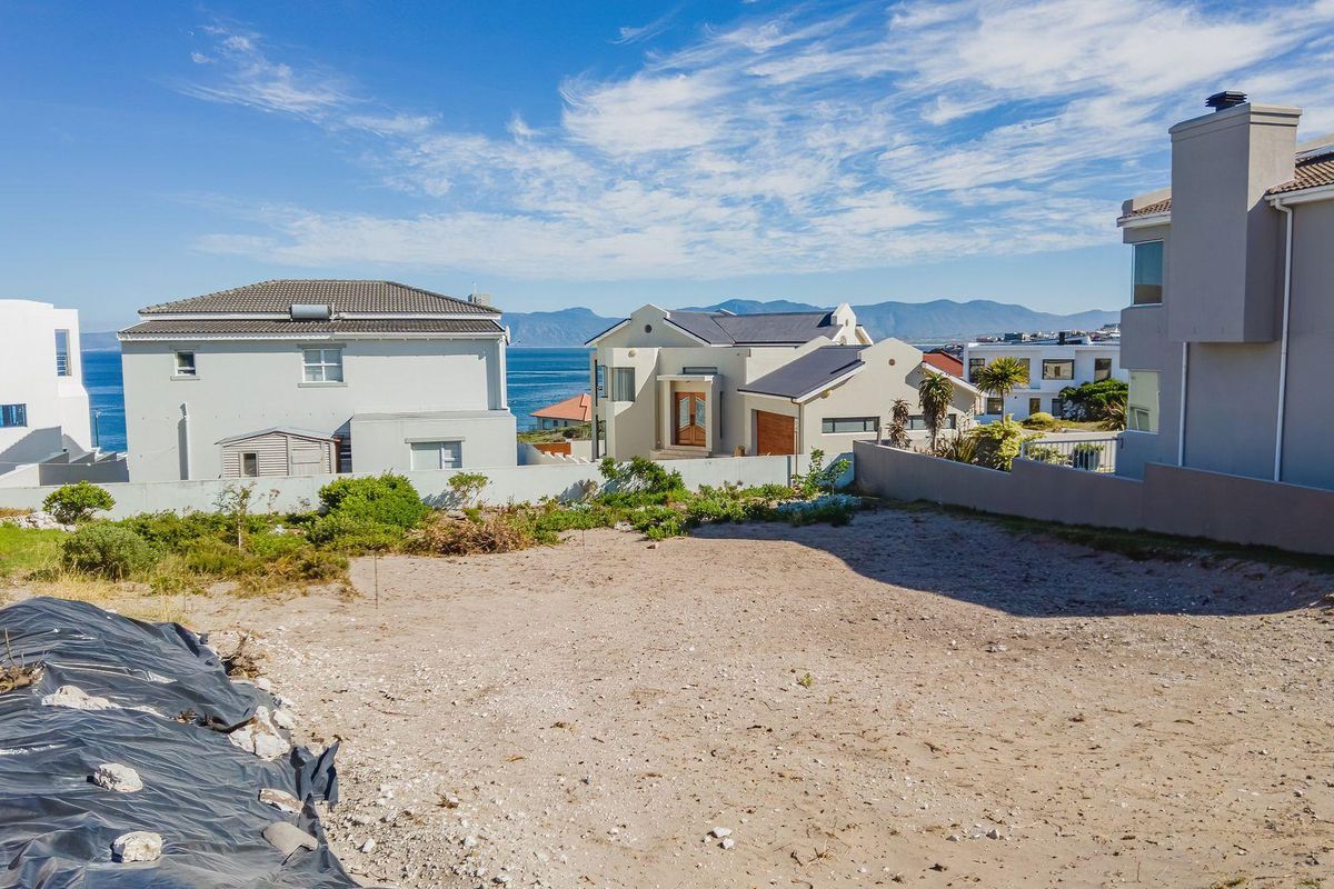 A vacant residential plot featuring boundary walls and scenic coastal views, situated in an established neighborhood.