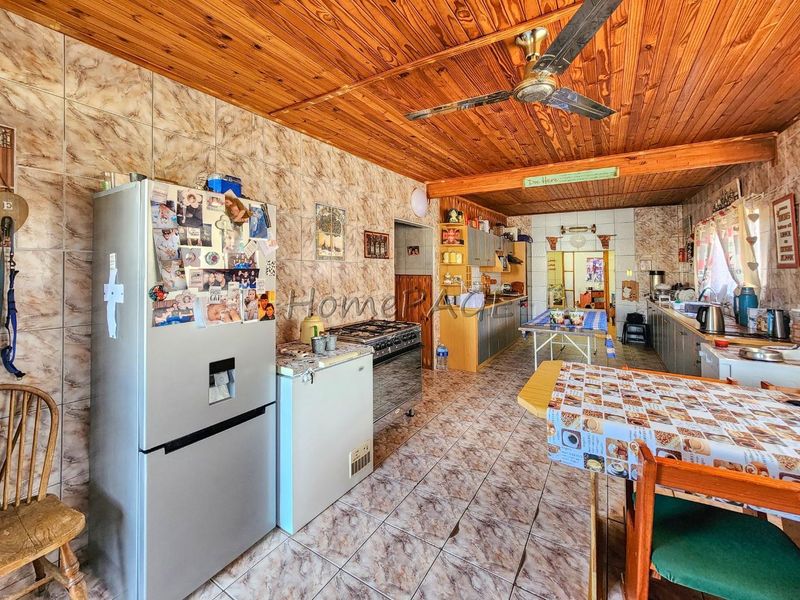 Spacious kitchen featuring timber ceilings, tiled walls and flooring, and built-in cabinetry with a gas stove.