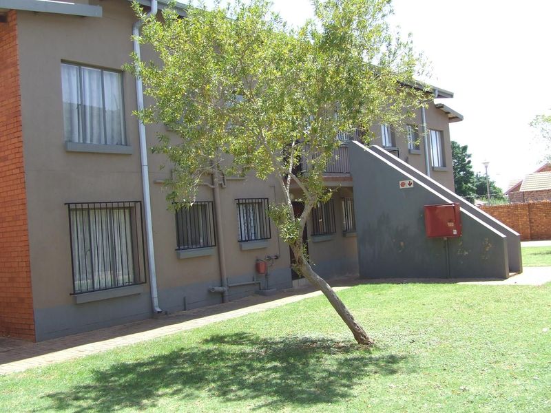 Rear view of a multi-story apartment building featuring security bars on windows, an external staircase, and a fire hose reel installation.