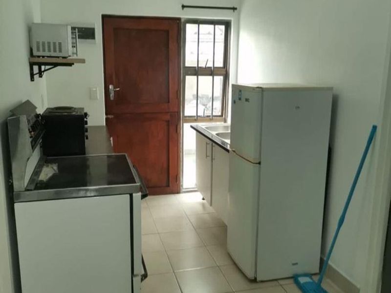 A compact kitchen featuring tiled flooring, built-in cabinetry, and a stainless steel sink, offering a functional space with potential for modernization.
