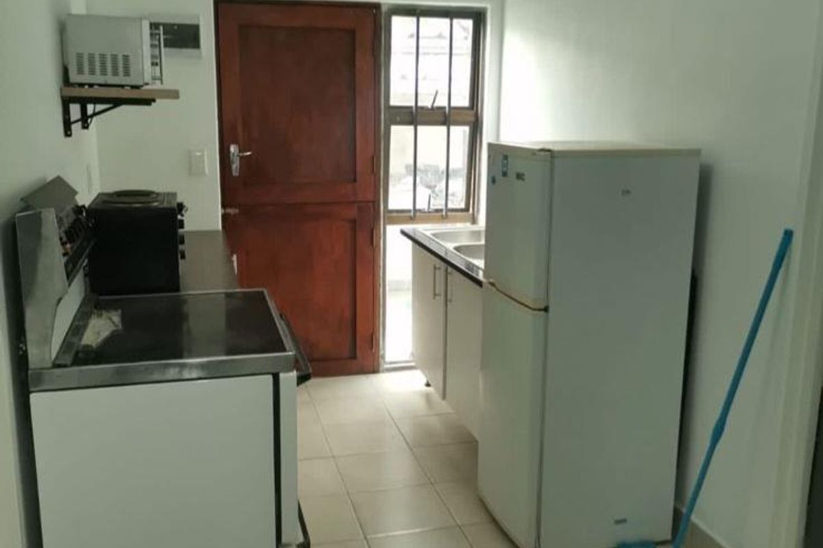 A compact kitchen featuring tiled flooring, built-in cabinetry, and a stainless steel sink, offering a functional space with potential for modernization.