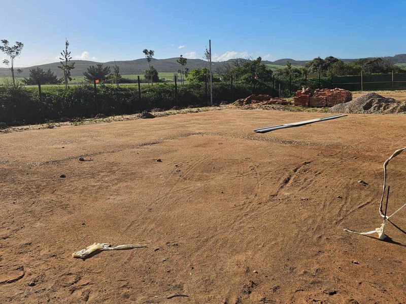 A vacant, cleared plot of land featuring perimeter fencing and distant mountain views, currently prepared for future landscaping or construction development.