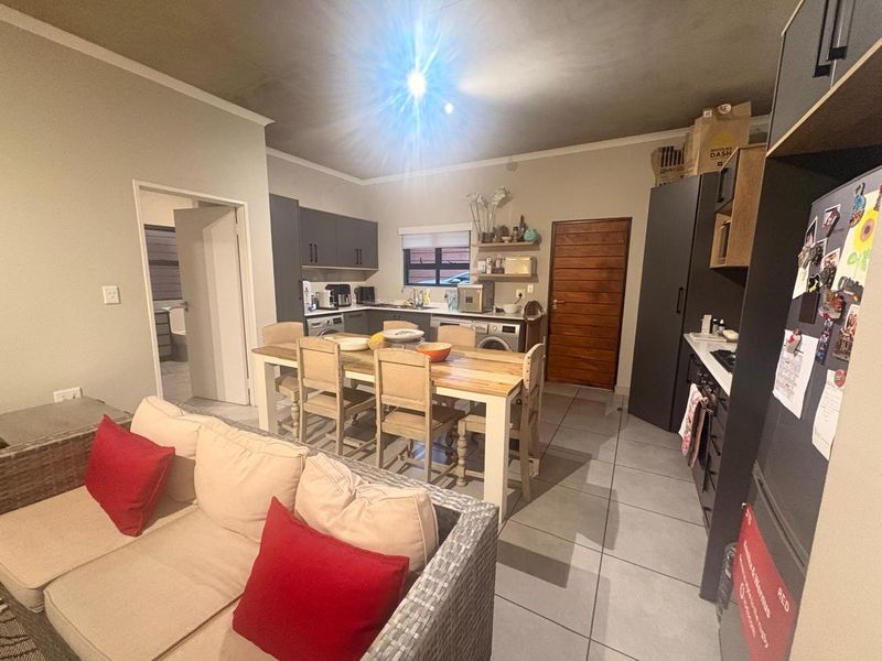 Open-plan kitchen and dining area featuring modern dark cabinetry, tiled floors, and direct access to adjacent rooms.