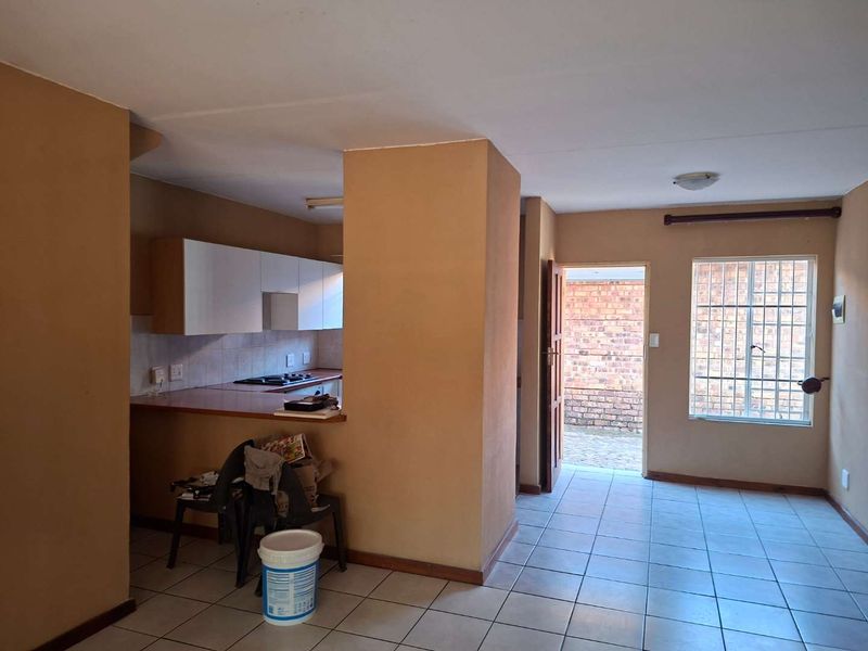 Open plan kitchen and living area featuring tiled flooring, built-in cabinetry with hob, and direct access to an exterior courtyard.