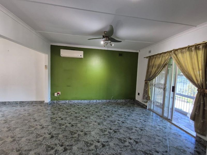 Spacious living area featuring tiled flooring, a ceiling fan, and a split-system air conditioner, with direct access to an outdoor patio through sliding glass doors.