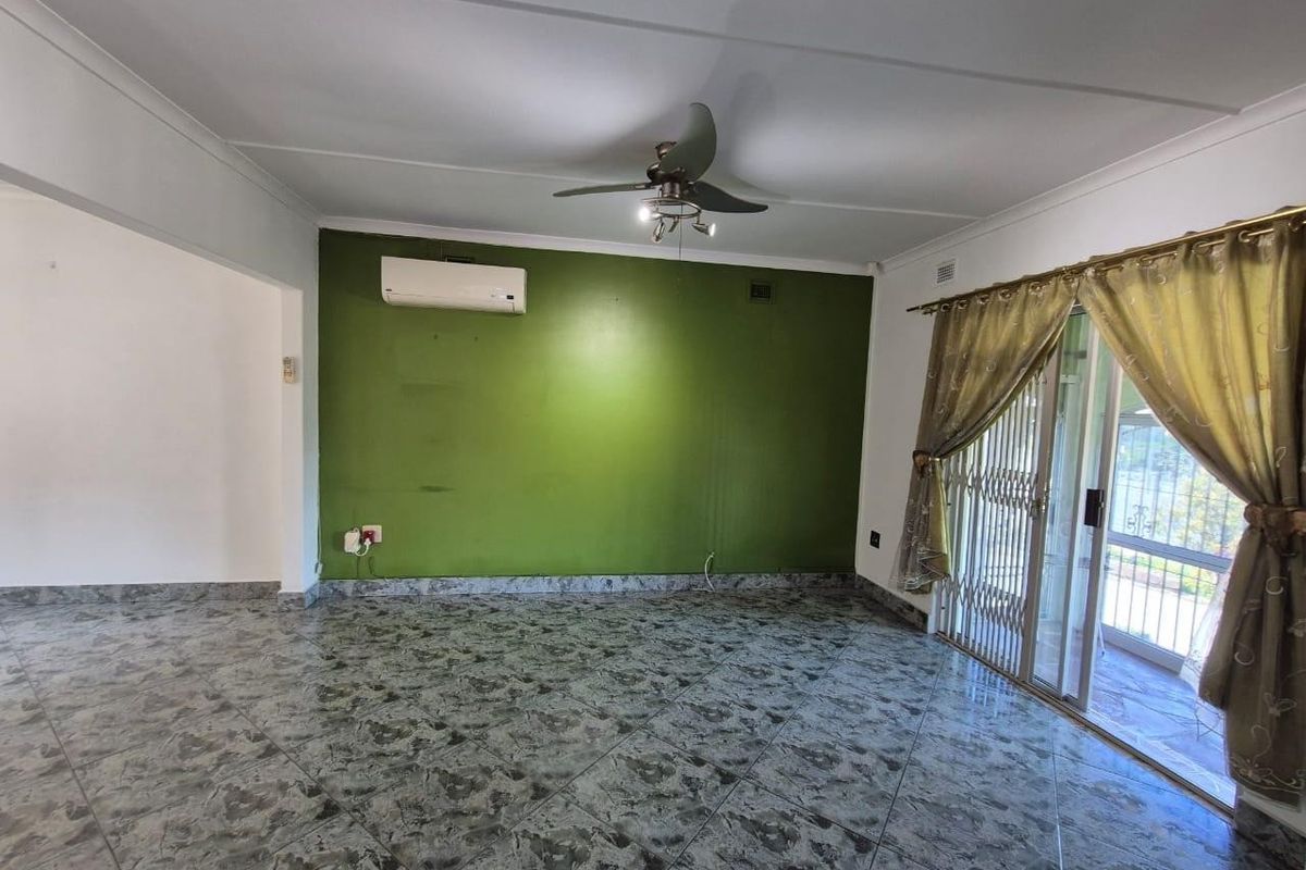 Spacious living area featuring tiled flooring, a ceiling fan, and a split-system air conditioner, with direct access to an outdoor patio through sliding glass doors.