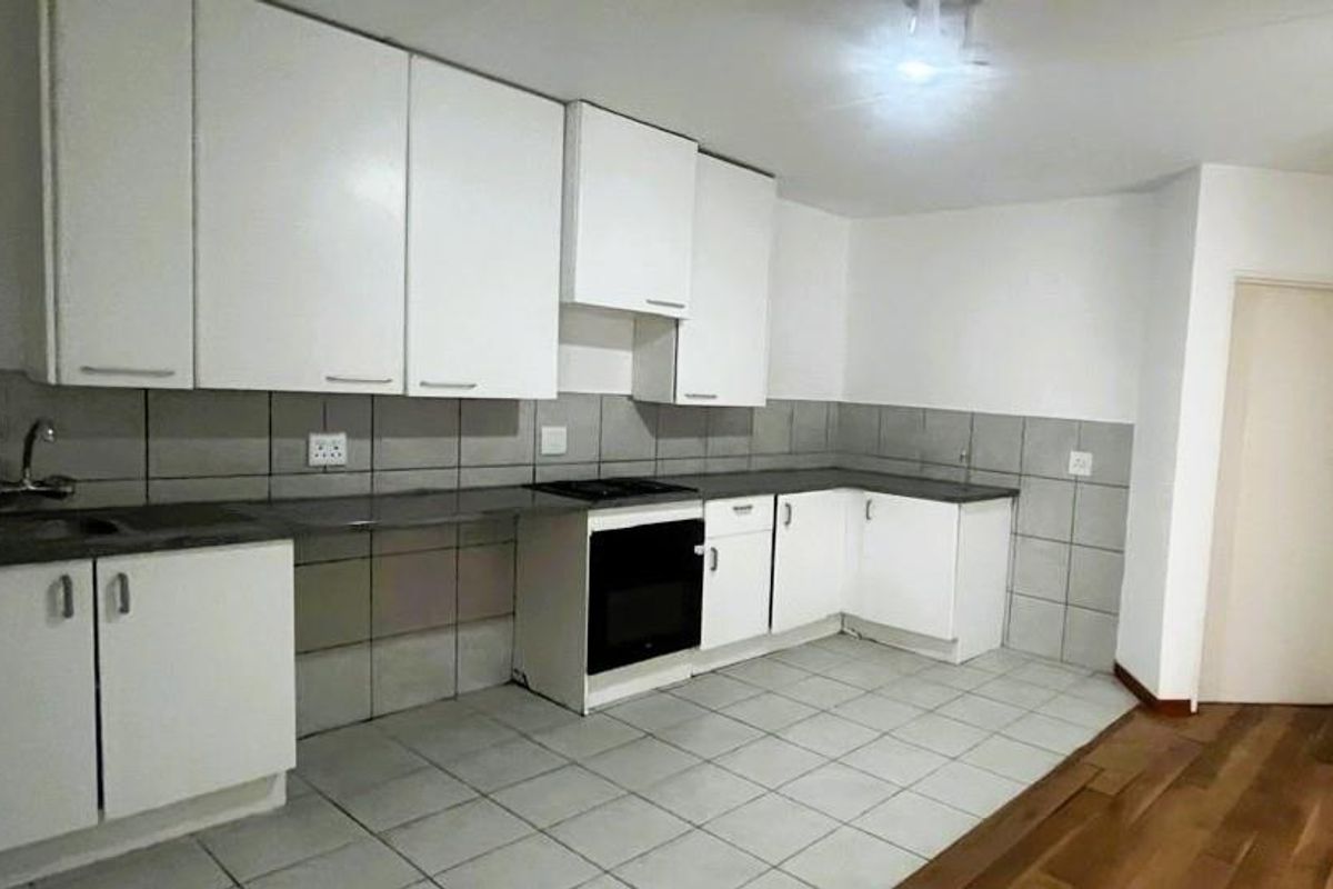 A functional kitchen featuring white cabinetry, dark countertops, a built-in oven, and tiled flooring, offering a clean and practical workspace.