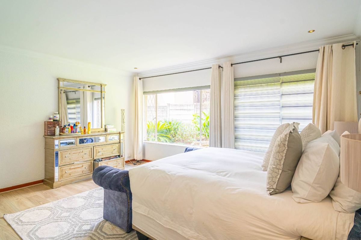 A bright and spacious bedroom featuring laminate flooring, recessed downlights, and large windows that provide ample natural light.