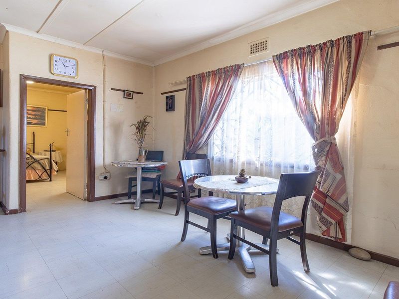 A dated living area featuring tiled flooring and visible wall cracks, offering a blank canvas for potential renovation and modernization.