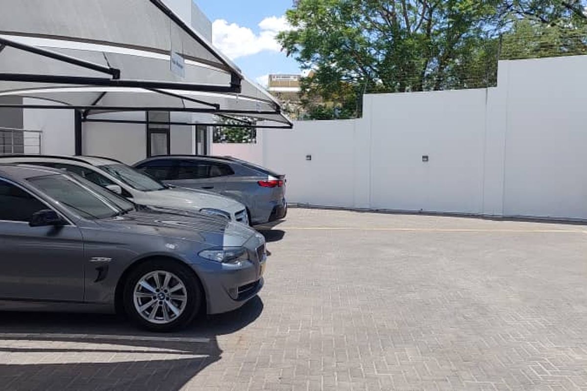 Paved outdoor parking area featuring shade cloth carports and secure perimeter walling.