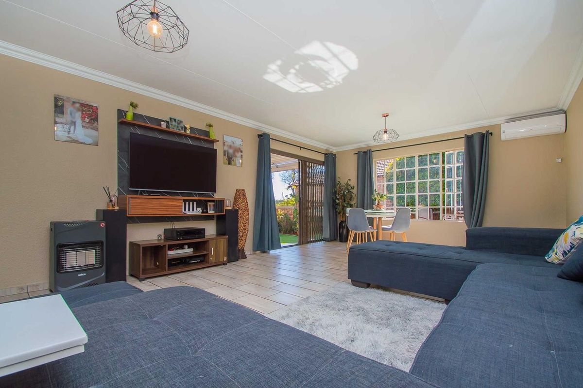 Spacious living room featuring tiled flooring, a wall-mounted air conditioner, and large sliding glass doors that provide natural light and access to the patio.