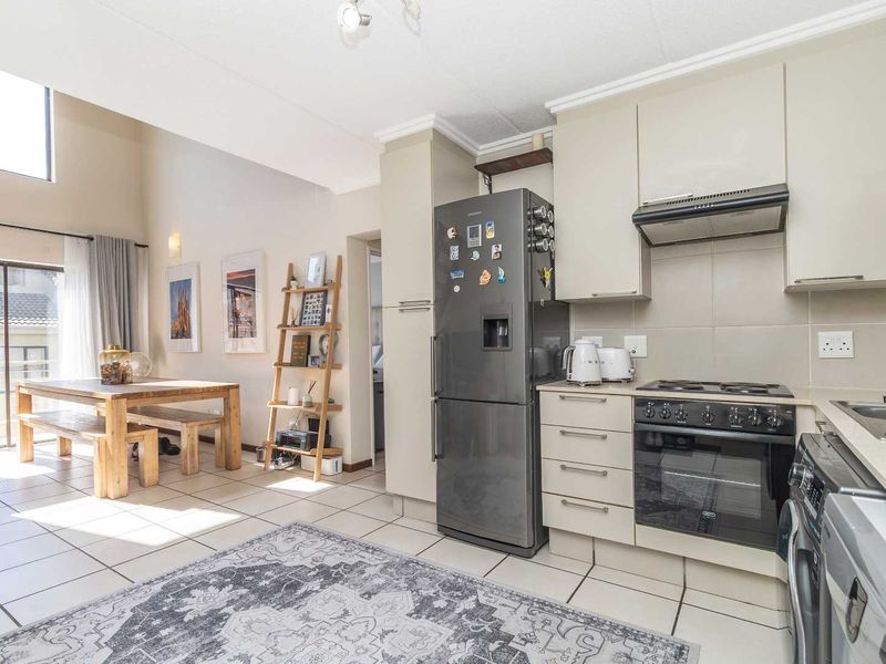 Open-plan living and kitchen area featuring tiled flooring, built-in cabinetry, integrated appliances, and a sliding door leading to an outdoor space.