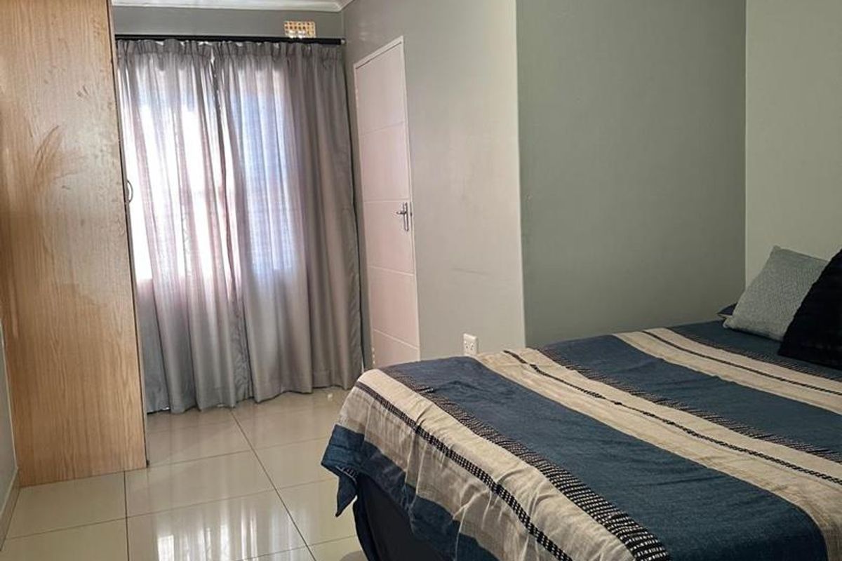 A functional bedroom featuring tiled flooring, a built-in wardrobe, and neutral wall finishes, providing a clean and practical living space.