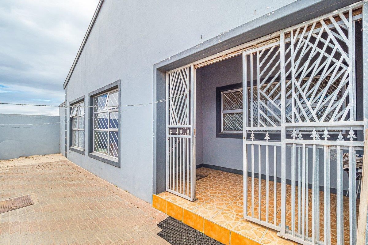 Exterior view of the property featuring a paved patio area, security gates, and tiled entrance steps.