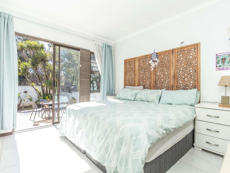 Bright bedroom featuring tiled flooring and large sliding glass doors providing direct access to an outdoor patio area.