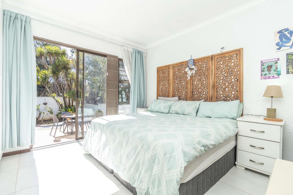Bright bedroom featuring tiled flooring and large sliding glass doors providing direct access to an outdoor patio area.