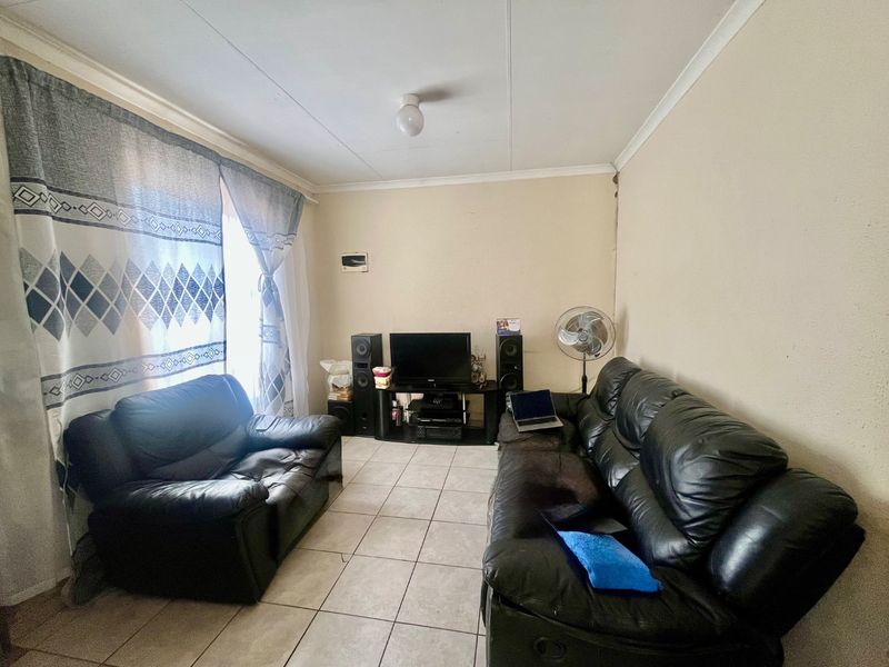 A living room featuring tiled flooring and coved ceilings, offering a functional space that could benefit from cosmetic updates and fresh paint.