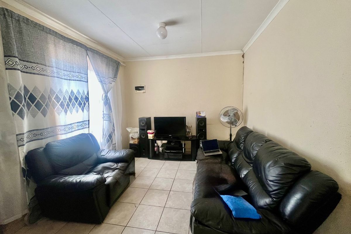 A living room featuring tiled flooring and coved ceilings, offering a functional space that could benefit from cosmetic updates and fresh paint.