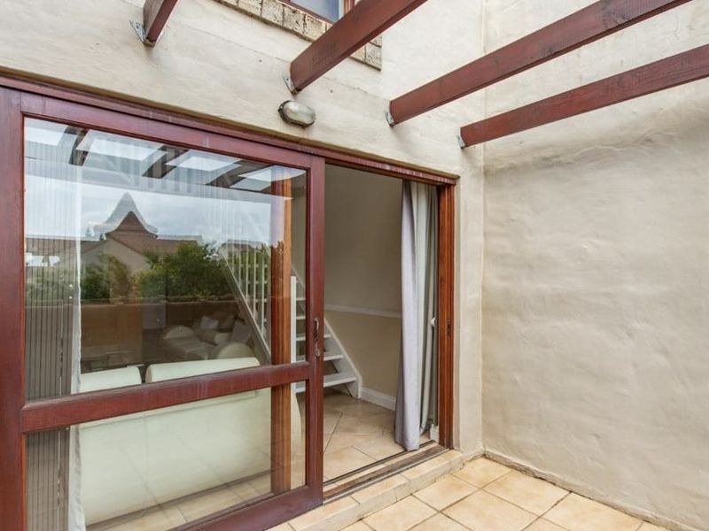 A private patio area featuring tiled flooring, a timber pergola structure, and a large sliding glass door providing access to the interior living space.