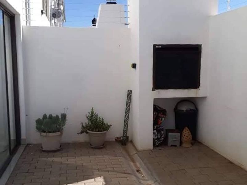 A private outdoor patio area featuring a built-in braai, paved flooring, and secure perimeter electric fencing.