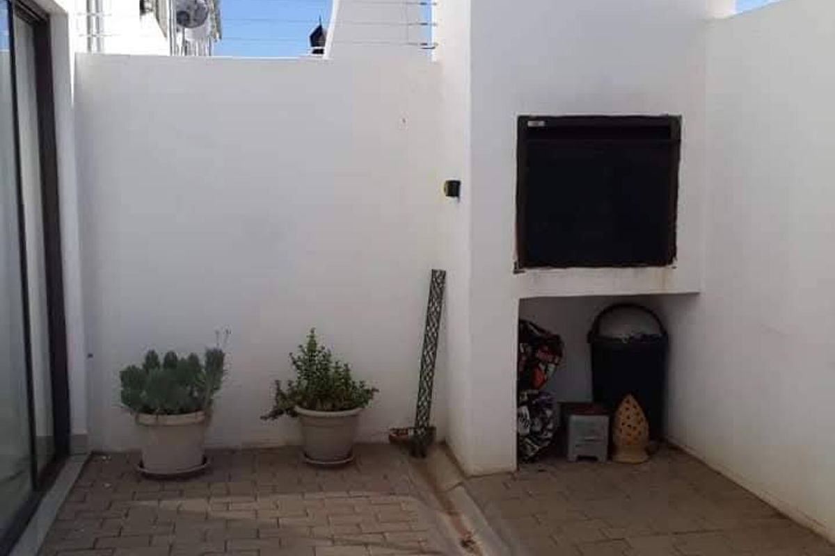 A private outdoor patio area featuring a built-in braai, paved flooring, and secure perimeter electric fencing.