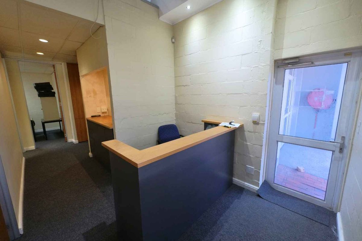 Office reception area featuring a built-in desk, recessed lighting, and direct access to an exterior space through a glass door.