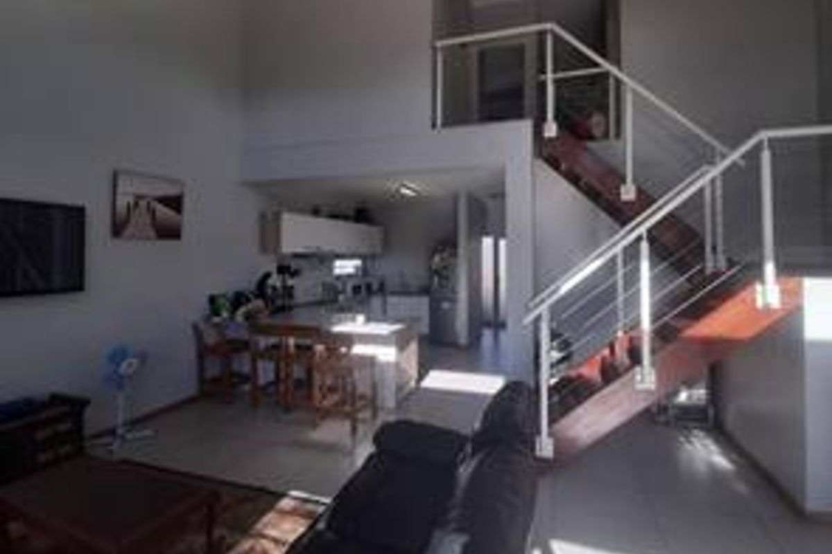 Open plan living and kitchen area featuring a staircase with metal balustrades and tiled flooring throughout.