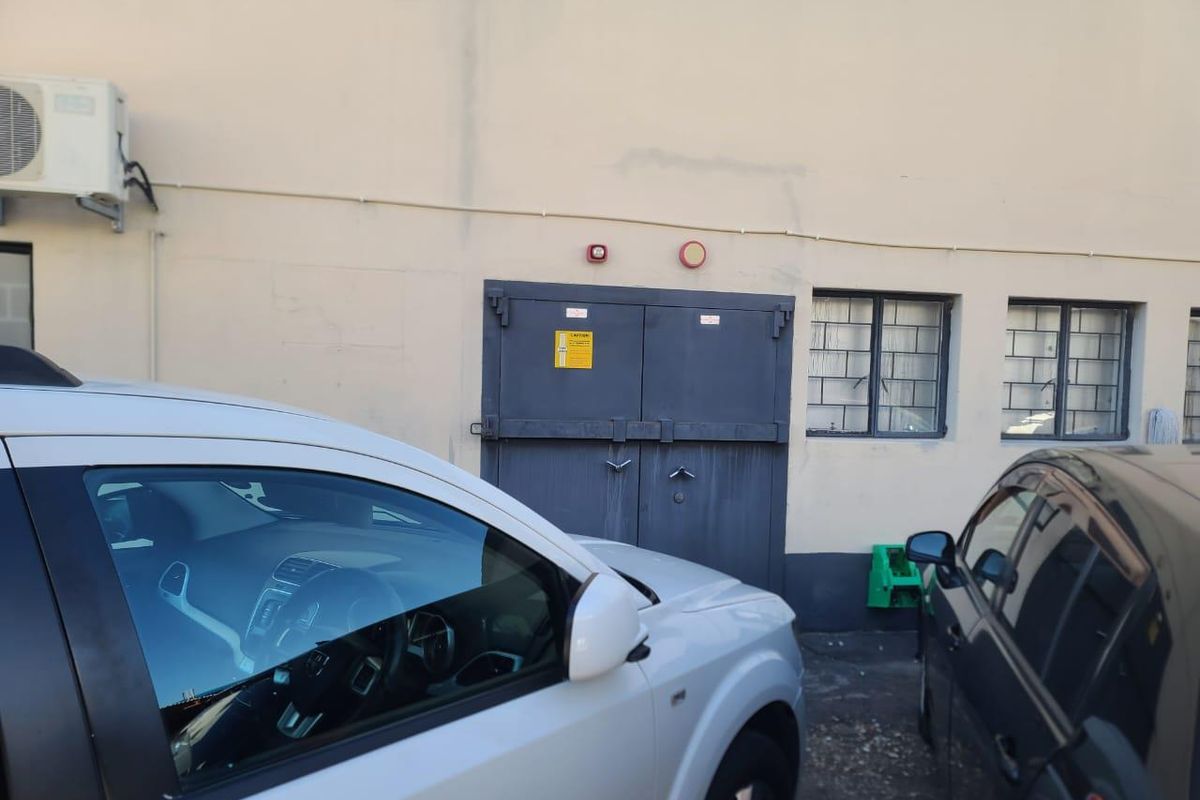 Exterior view of an office building featuring a secure metal service door, security-barred windows, and an external air conditioning unit.