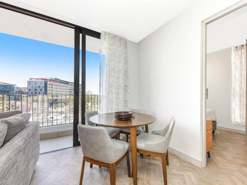 Bright living area featuring elegant herringbone timber flooring and large sliding glass doors opening onto a private balcony with urban views.