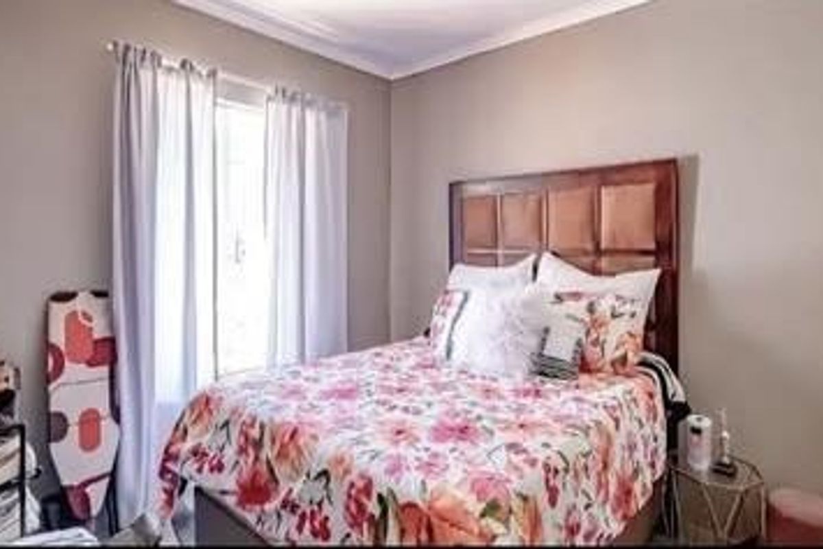 A cozy bedroom featuring neutral wall tones, a large window with curtains, and a built-in headboard area.