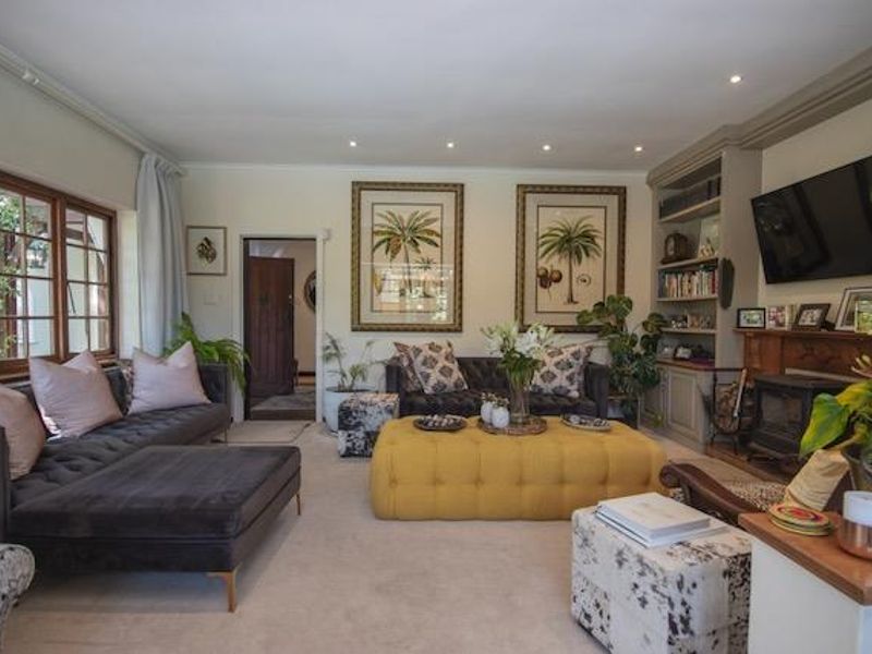 A comfortable living room featuring a built-in shelving unit, a wood-burning fireplace, and large timber-framed windows providing natural light.