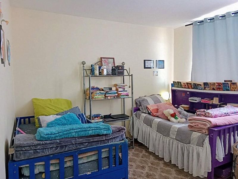 A bedroom featuring neutral walls and a window with a curtain rod, providing a functional space for sleeping or study.