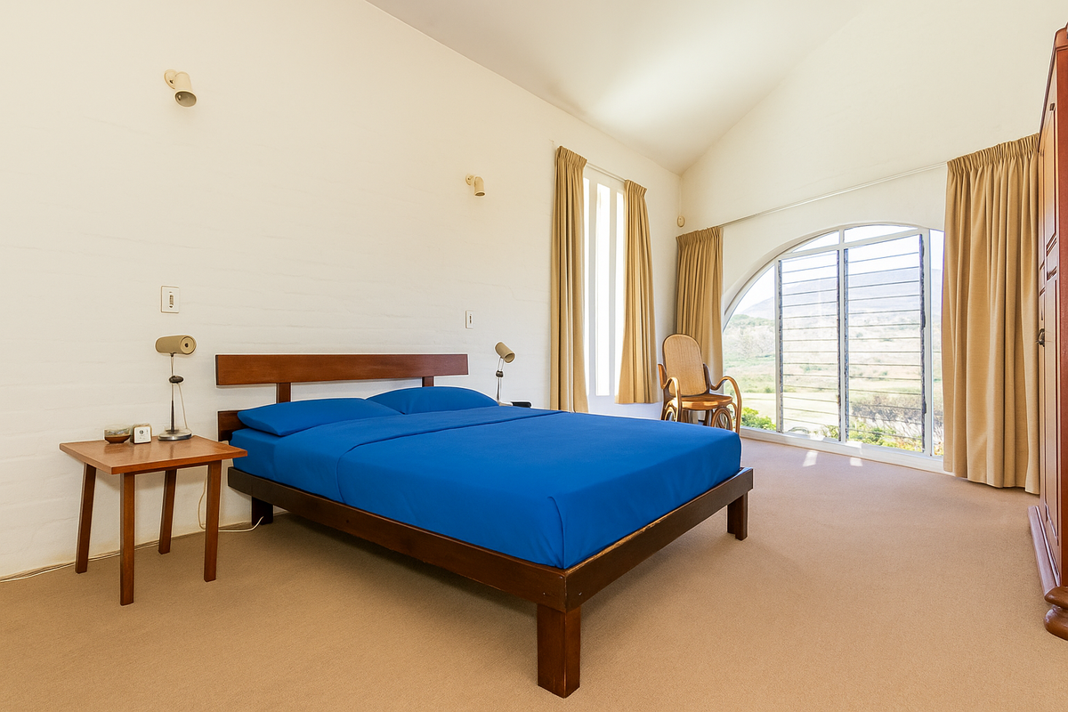 Spacious bedroom featuring high vaulted ceilings, carpeted flooring, and a large arched window offering natural light and scenic views.