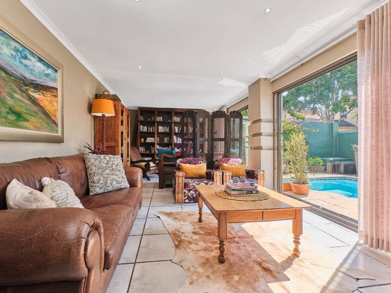 Spacious living room featuring tiled flooring, recessed lighting, and large sliding glass doors that provide seamless access to the outdoor pool area.