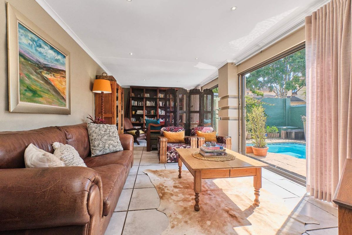Spacious living room featuring tiled flooring, recessed lighting, and large sliding glass doors that provide seamless access to the outdoor pool area.