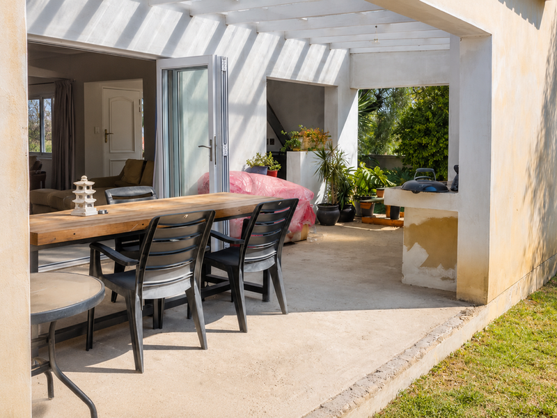 Covered outdoor patio featuring a pergola, built-in masonry counter, and bi-fold doors providing seamless access to the interior living space.