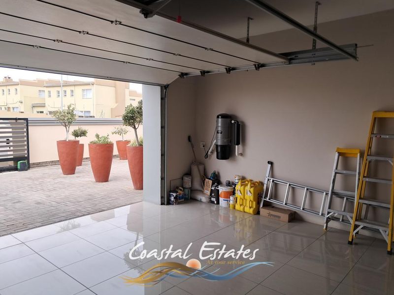 Spacious garage featuring polished tiled flooring, a sectional overhead door, and a built-in central vacuum system, with direct access to an outdoor patio area.