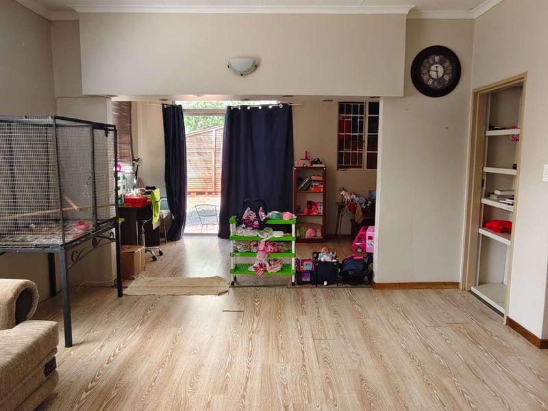 Spacious living area featuring light-toned laminate flooring, built-in shelving, and direct access to the outdoor area through a sliding door.