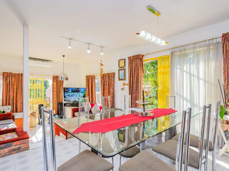 Bright open-plan living and dining area featuring tiled floors, modern lighting, and sliding glass doors providing direct access to the garden.