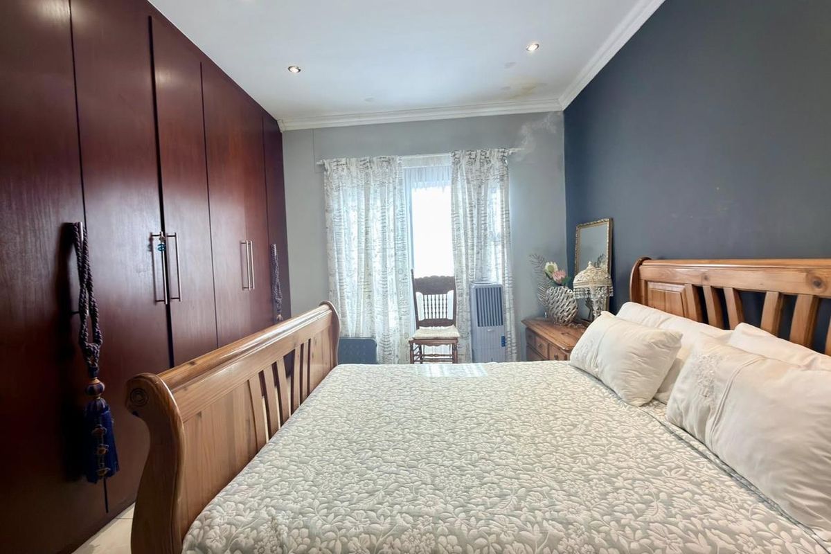 A bedroom featuring built-in dark wood cabinetry, recessed ceiling lighting, and a dark accent wall.